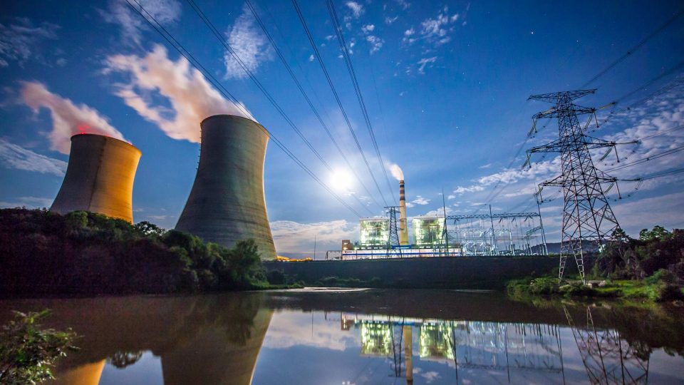 Power plant with stacks and power lines next to a river