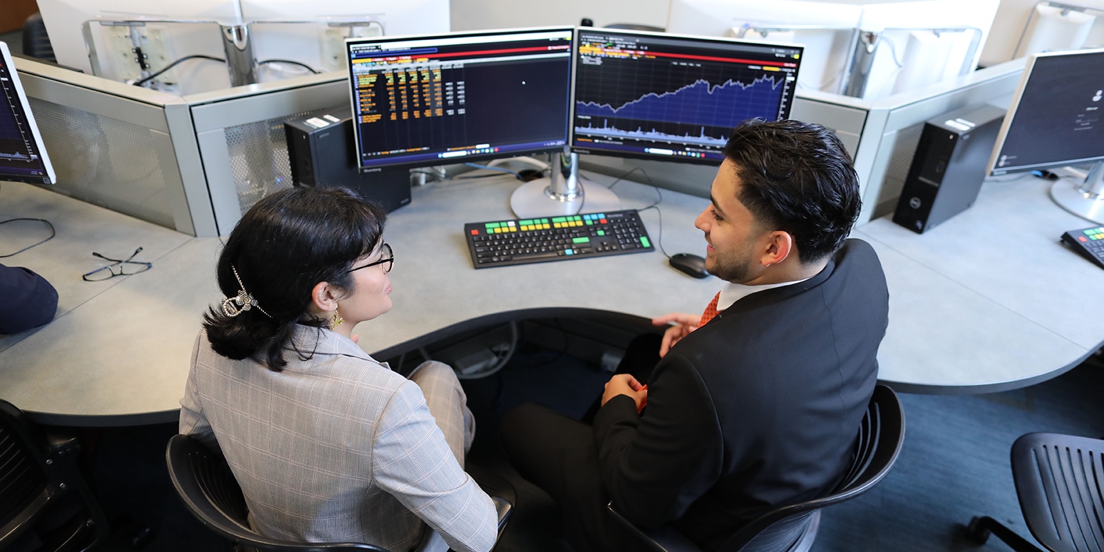 A UF Warrington instructor meets with an MS in Finance student about their project, which includes data and a graph on two computer monitors