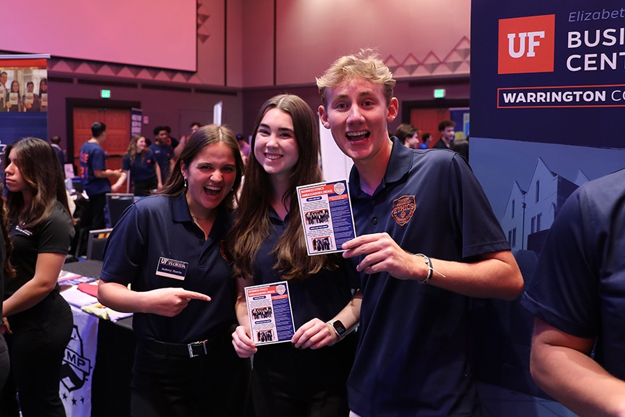 Warrington College of Business students hold up brochures during a fair for the University of Florida's undergraduate minors