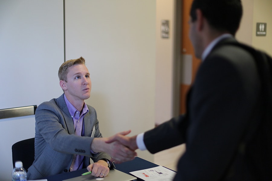 A University of Florida student shakes hands with a representative from the Warrington College of Business after learning about the Business Administration minor