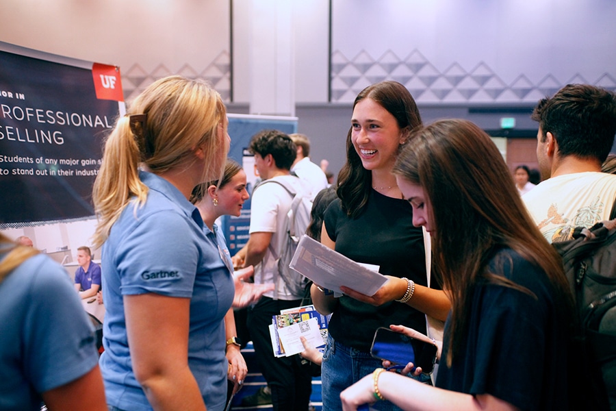 Two University of Florida students discuss the Professional Selling Minor with a program representative from the Warrington College of Business