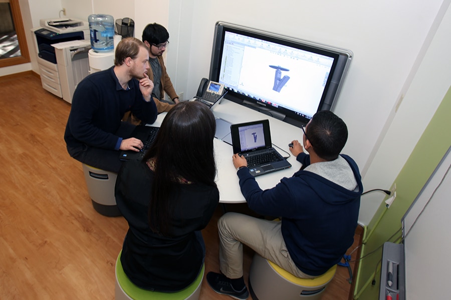 Group of students working around a monitor together. 