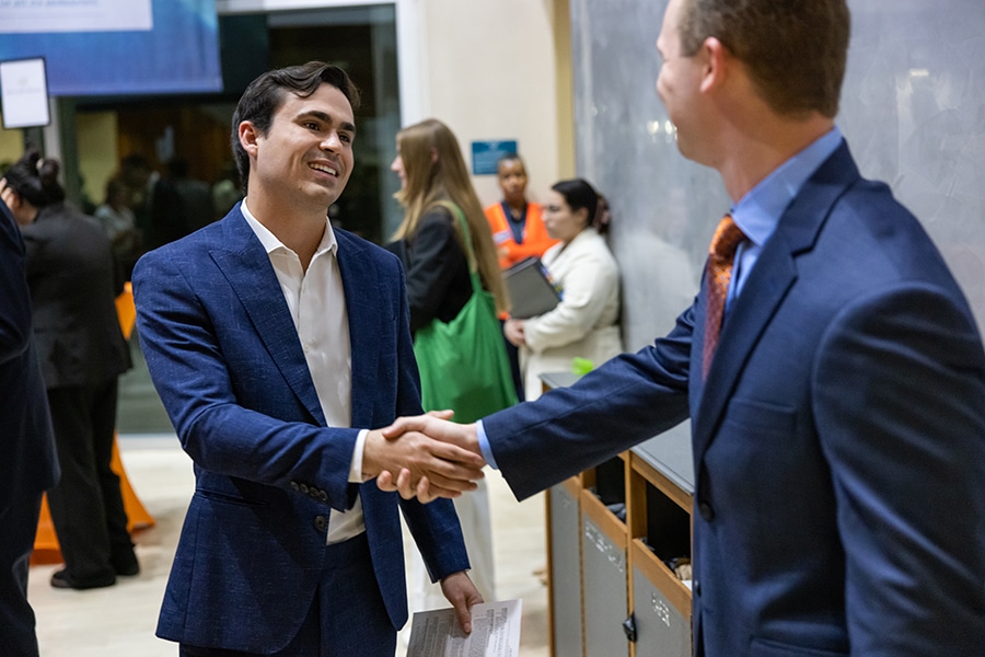 A professionally dressed male student shaking hands with an employer. 