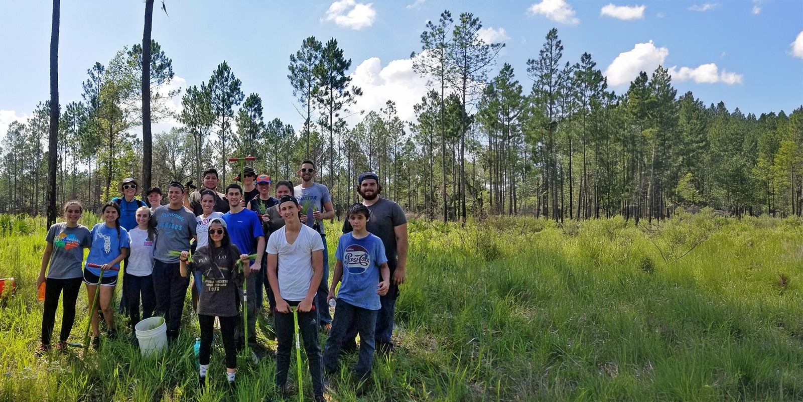 Group of entrepreneurship students posing outdoors during a tree planting trip. 