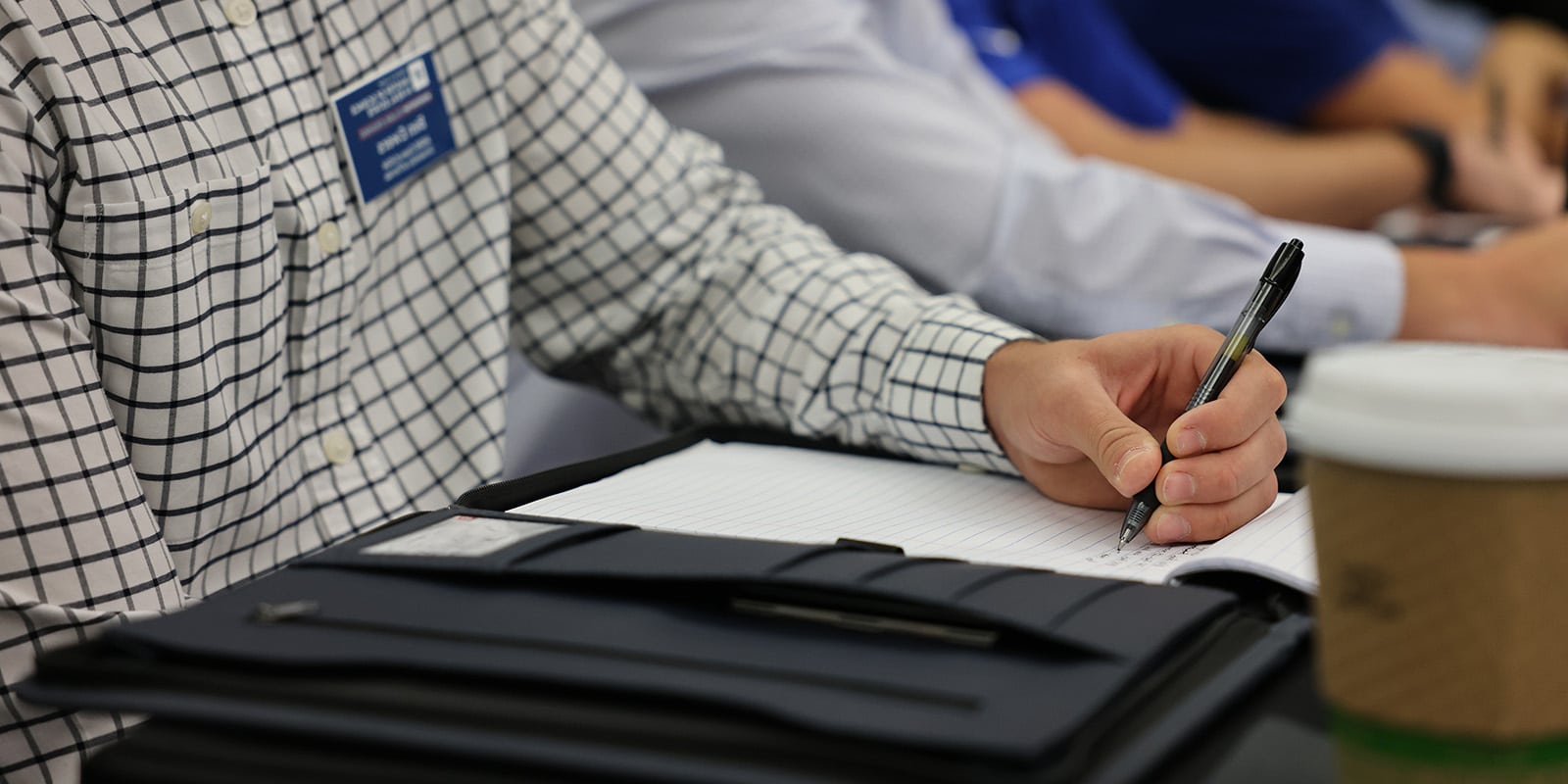 Closeup of a man's hand writing on a pad of paper.