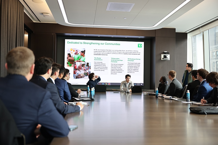 Students listening to a lecture around a conference table. 