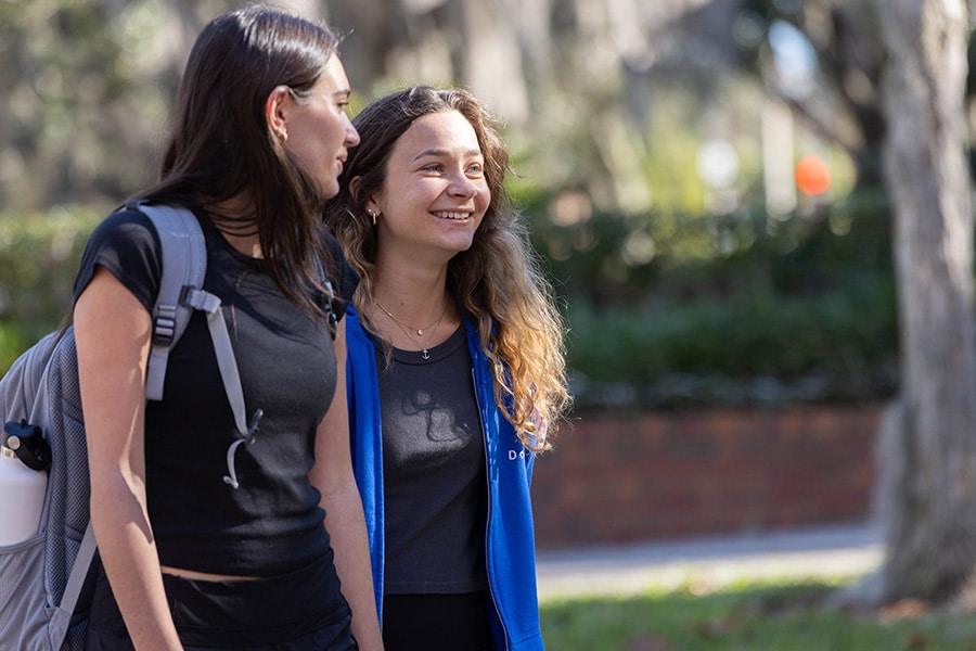 Two young women walk through campus.