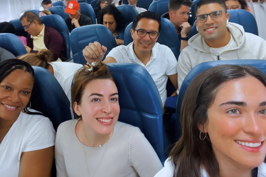 Group of smiling UF graduate business students seated on a plane for an international trip