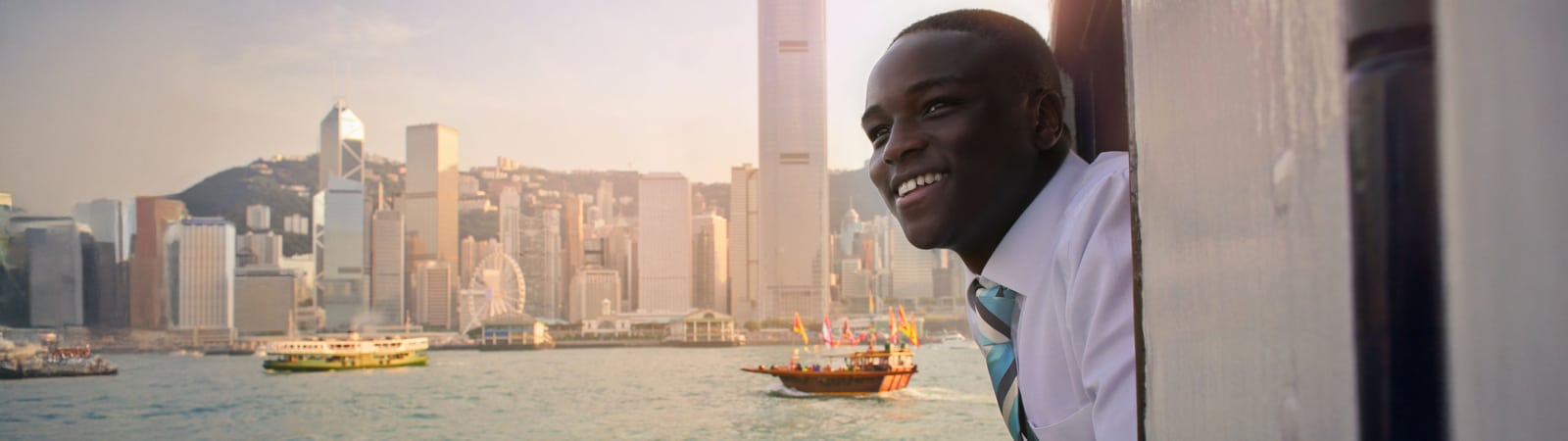 Smiling business student on a boat overlooking the Hong Kong skyline