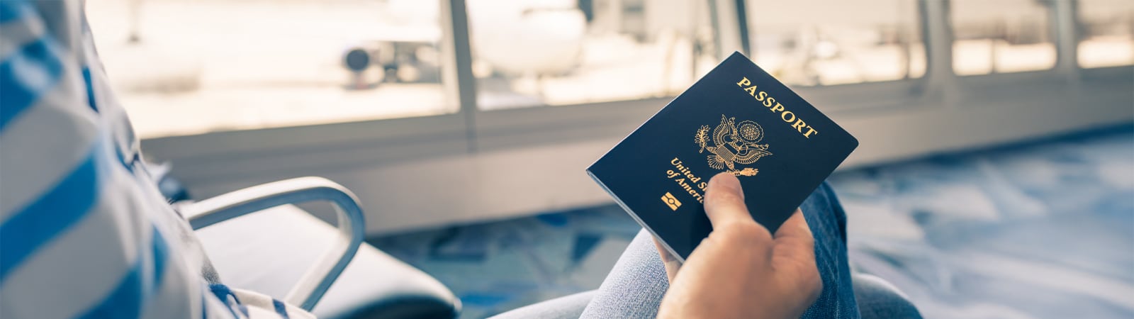 Close-up of a person holding a U.S. passport at an airport gate