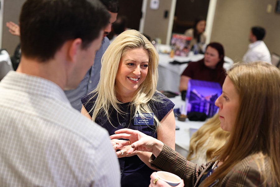 MBA students talking together at a summit for their program.