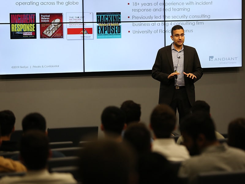A man in professional attire speaking in front of an audience.