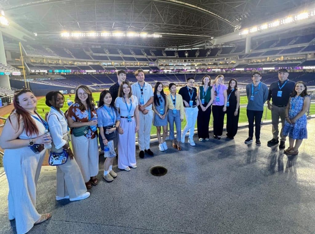 Students stand in front of Miami Marlins baseball field. 