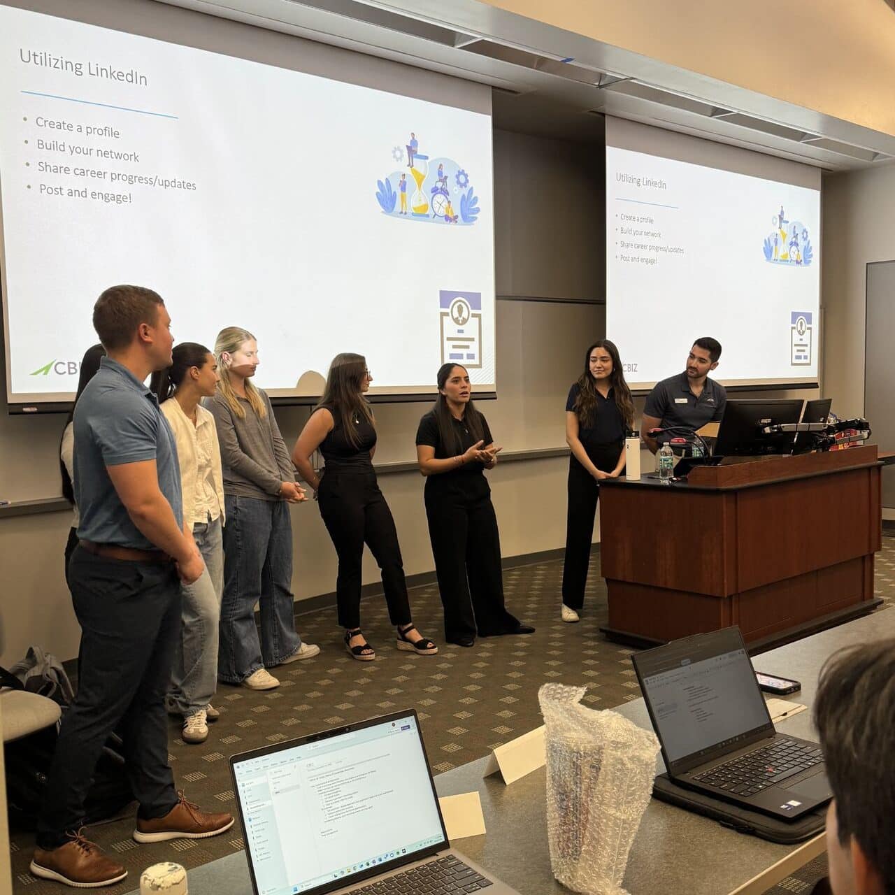 CBIZ guest speakers speaking in front of a classroom with a powerpoint slideshow 
