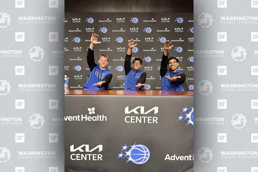 Tyler Rasmussen, Ahan Soni and Archit Namboodiri doing the Gator chomp at a KIA center and orlando magic table
