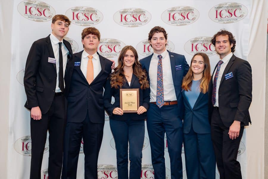 uf sales team standing and smiling while holding a plaque for second place