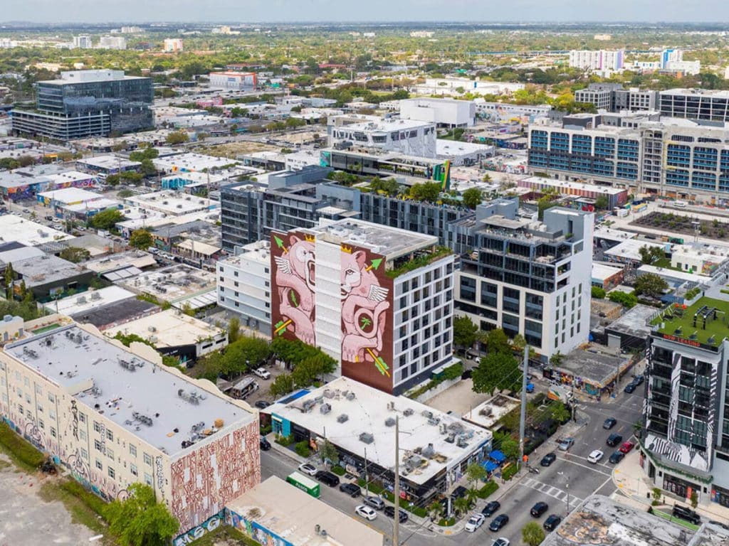 An aerial view of Miami's Wynwood neighborhood with a building in the middle that has a mural on one side and windows on another.
